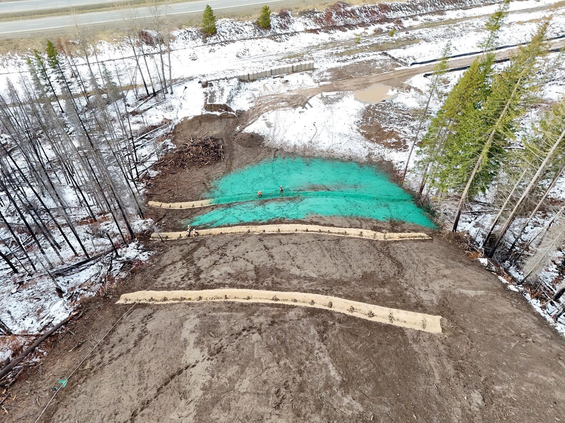 Aerial drone view of fresh green hydroseed application beside a creek on a remote site